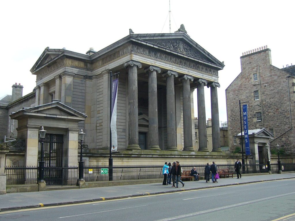 Photo of the front of Surgeon's Hall Museum. The building has columns and a fence in front of it. Photo from Wikicommons